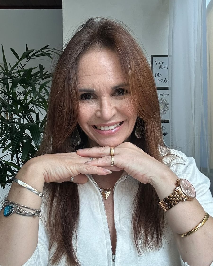 Katia Marchini, sorrindo, com as mãos sob o queixo